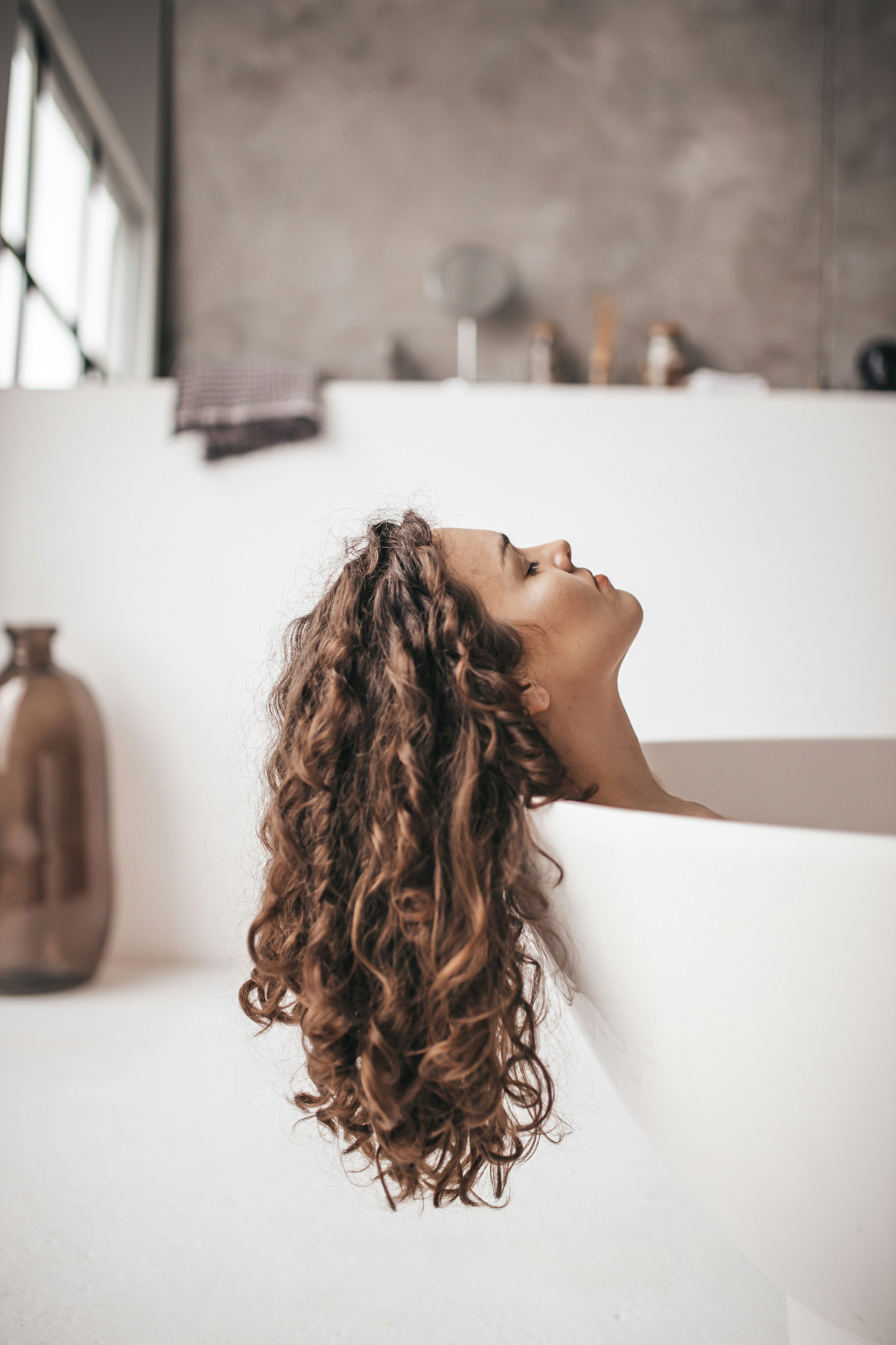 Model with auburn curly hair, the result of a signature treatment at Twonine0 Beauty Salon